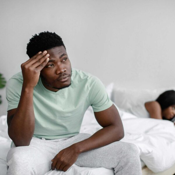 Troubled couple experiencing conflict in a bedroom setting, expressing emotional distress.