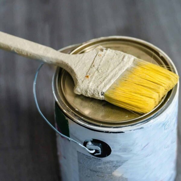 This is a photograph of a paint can and a paintbrush. Stain and paint can be used to refresh furniture made of wood.