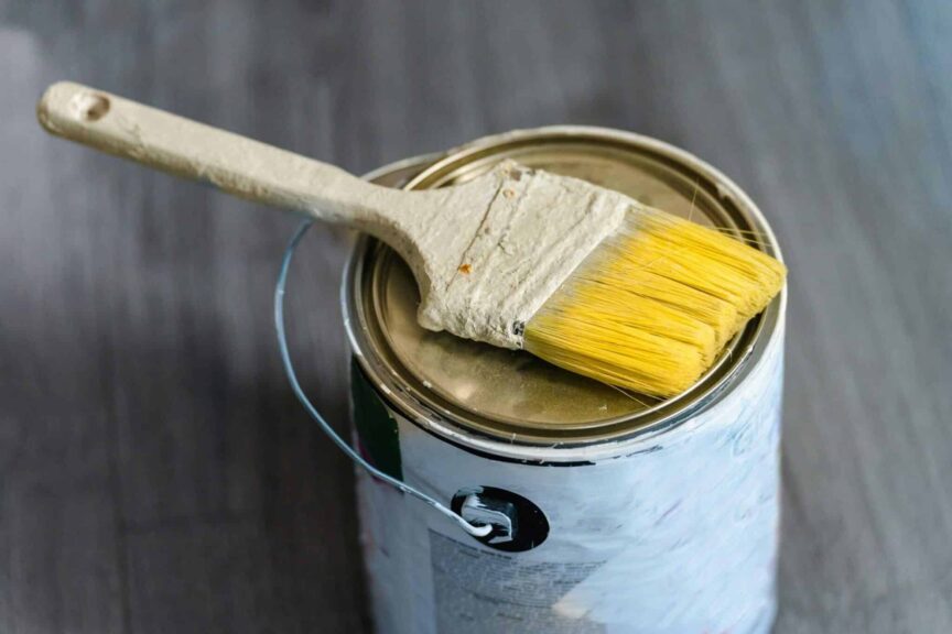 This is a photograph of a paint can and a paintbrush. Stain and paint can be used to refresh furniture made of wood.