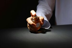 A hand elegantly holding a perfume bottle against a dark backdrop, highlighting luxury fragrance. Colognes