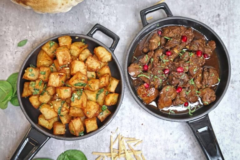 Tasty roast potatoes and beef stew garnished with herbs and pomegranate, perfect for a hearty meal. cast iron, carbon steel