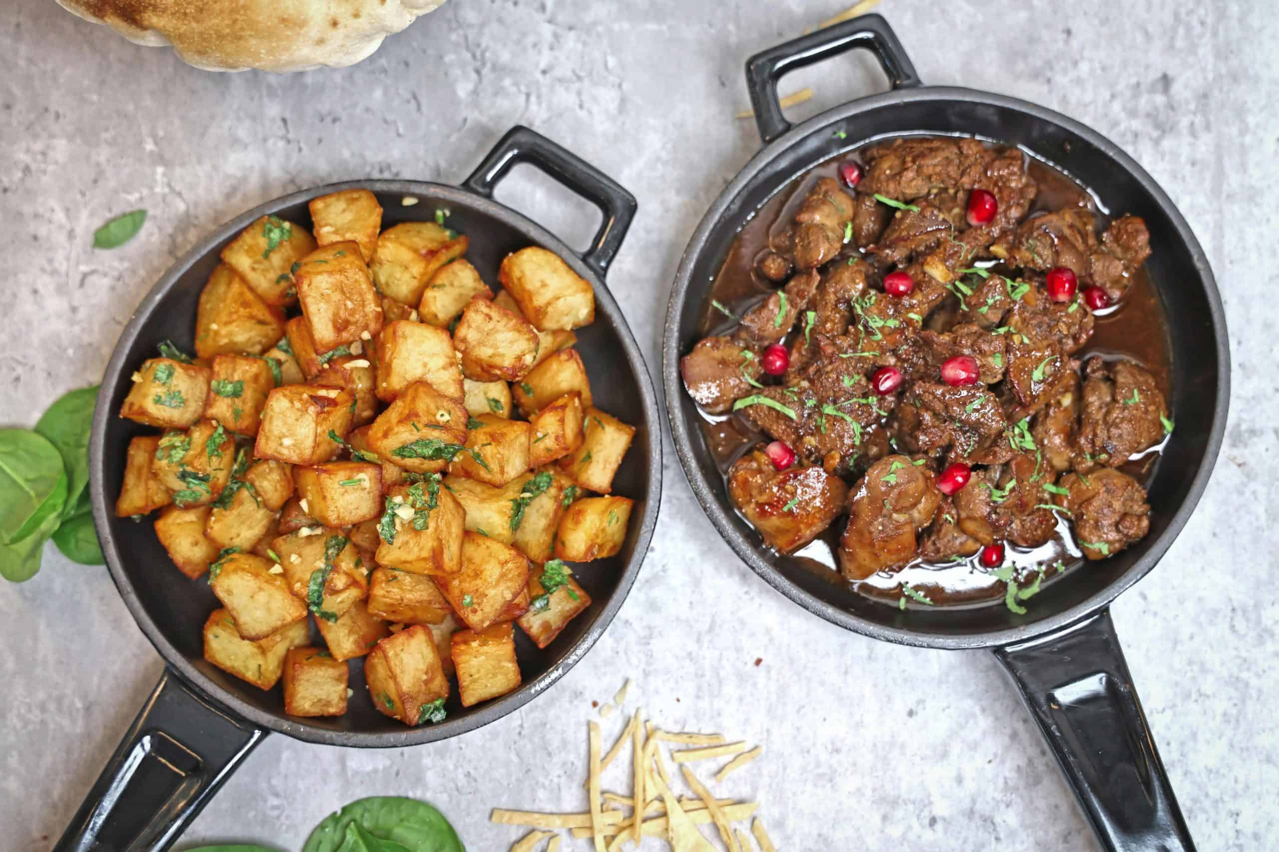 Tasty roast potatoes and beef stew garnished with herbs and pomegranate, perfect for a hearty meal. cast iron, carbon steel