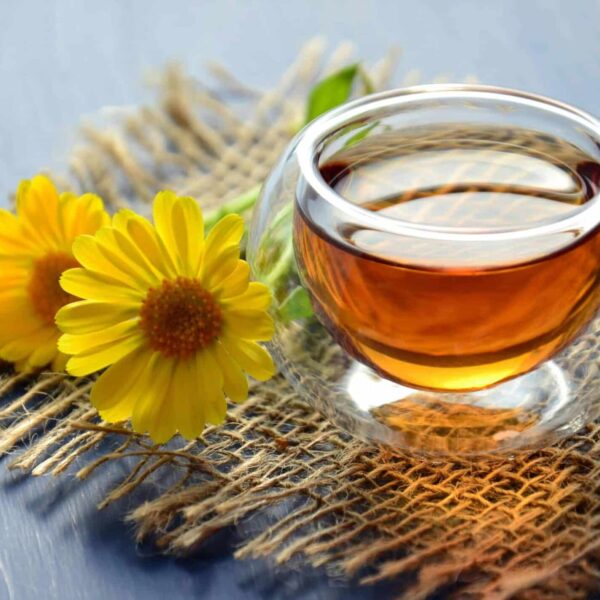 Glass cup of herbal tea with yellow flowers on a textured background. , coffee alternatives