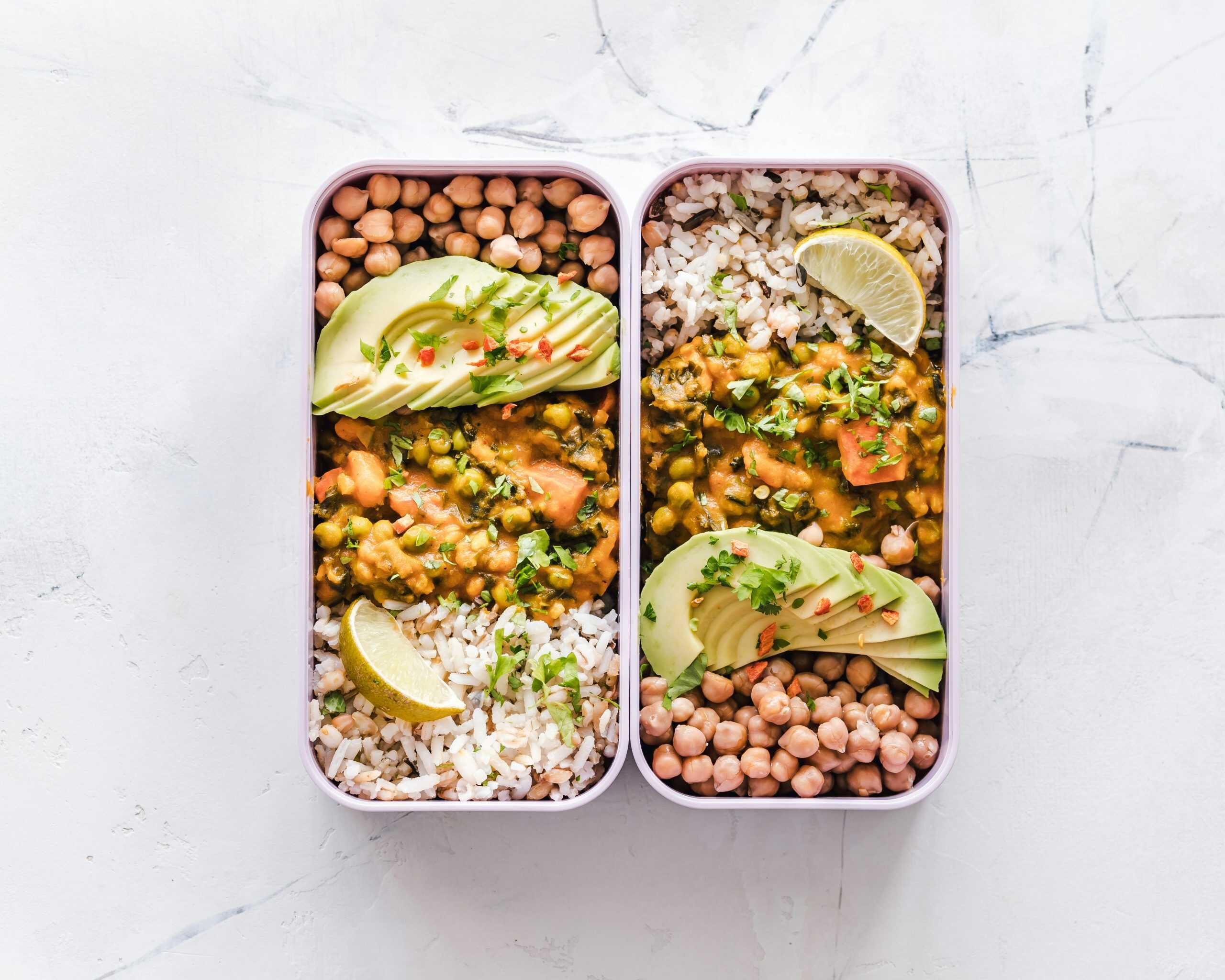 Delicious vegan lunchboxes featuring chickpeas, rice, avocado, and curry on a white background. TikTok