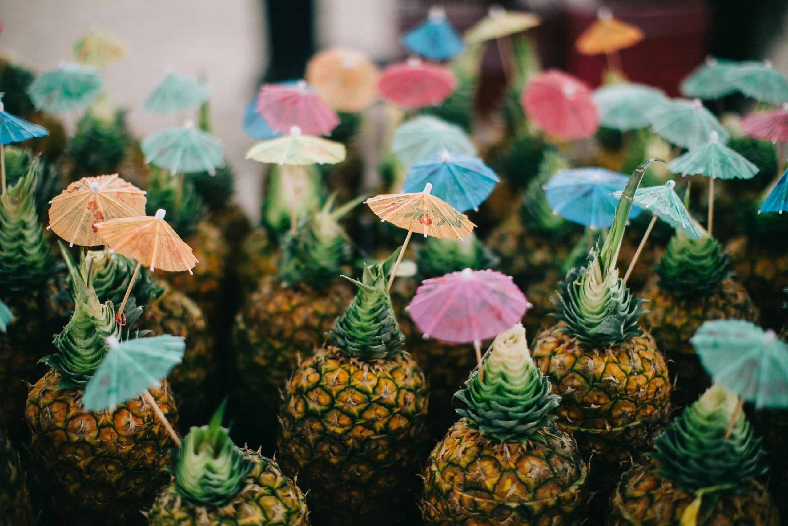 Pineapples topped with vibrant cocktail umbrellas creating a fun, tropical theme.
