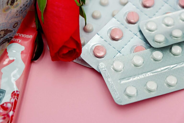 Pills and red rose on pink background, symbolizing healthcare and romance. hormonal birth control