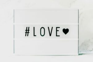 Contemporary minimalist sign displaying '#LOVE' in text with a black heart on a white background. venus in leo, love, bold love, emotional shifts,