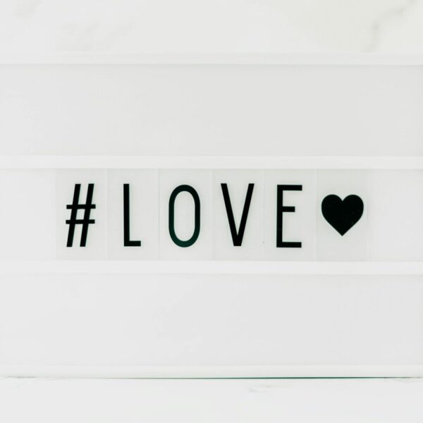 Contemporary minimalist sign displaying '#LOVE' in text with a black heart on a white background. venus in leo, love, bold love, emotional shifts,