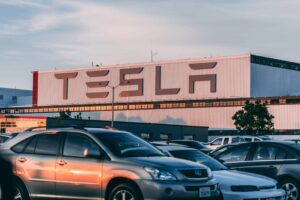 Tesla factory with parked cars during sunset, showcasing modern automotive industry vibes. Tesla Model 3