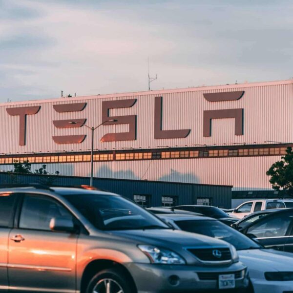 Tesla factory with parked cars during sunset, showcasing modern automotive industry vibes. Tesla Model 3