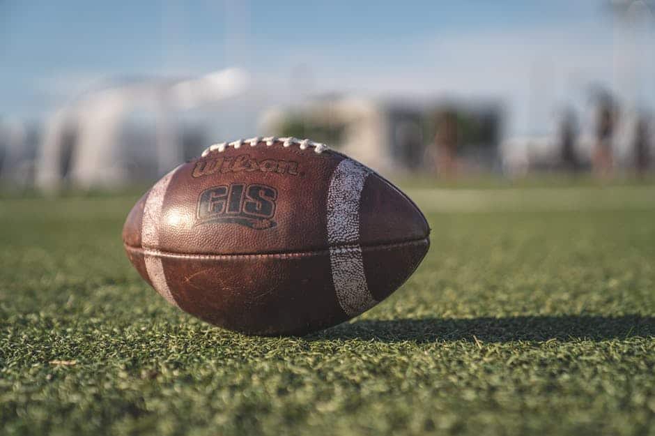 nfl preseason, Close-up of a Wilson football on green grass in an outdoor sports setting, perfect for sports-themed visuals.
