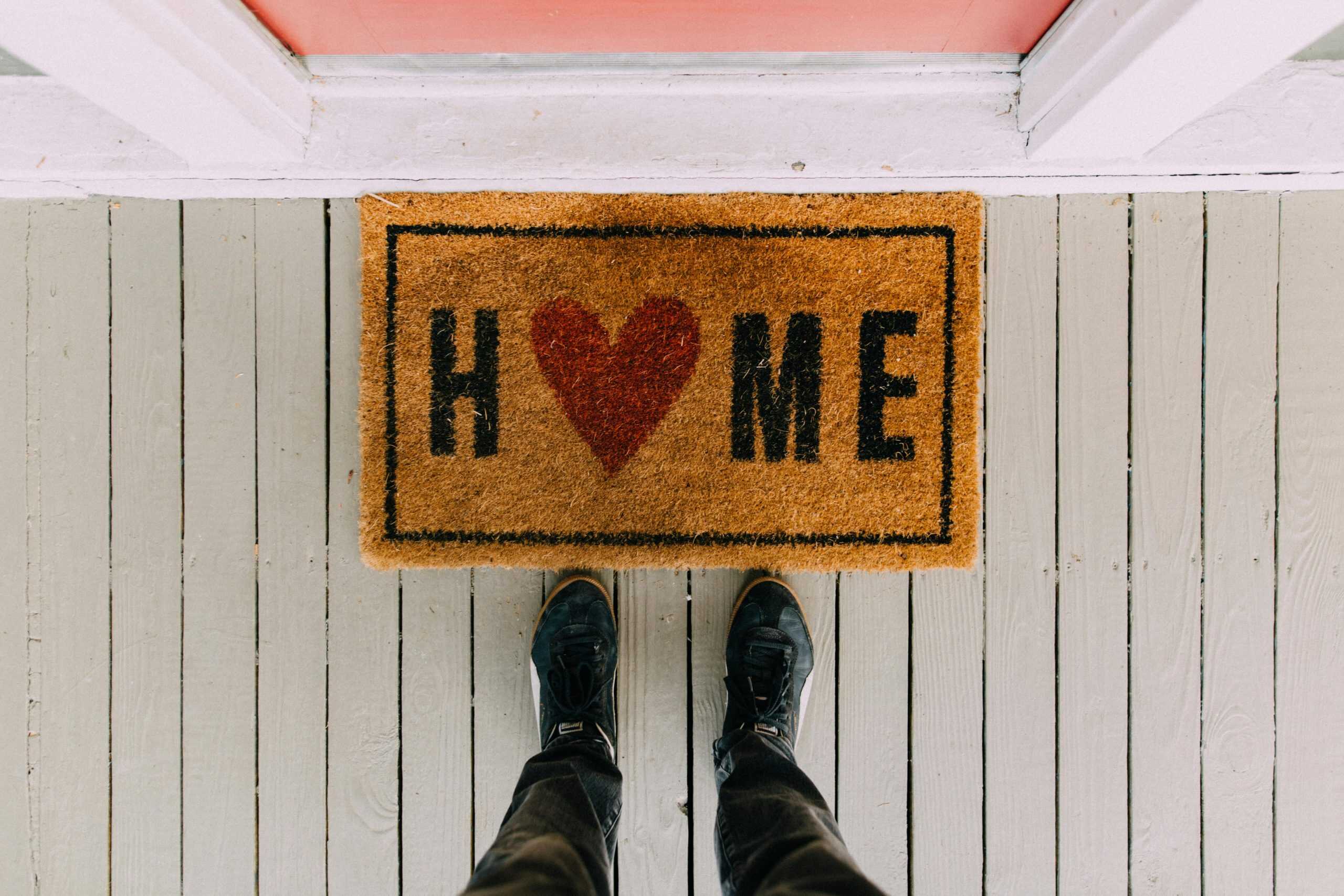 A creative doormat with heart motif symbolizing home at a front porch entrance. Redemption