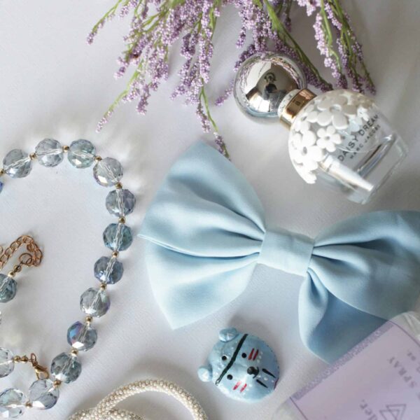 Flat lay of lavender, bow, jewelry, and perfume creating an elegant arrangement on a white background.
