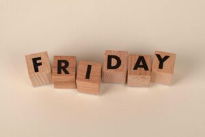 Wooden letter blocks spelling out 'Friday' on a neutral beige background. daily devotion