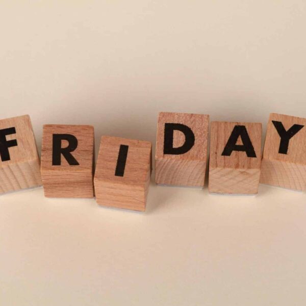 Wooden letter blocks spelling out 'Friday' on a neutral beige background. daily devotion