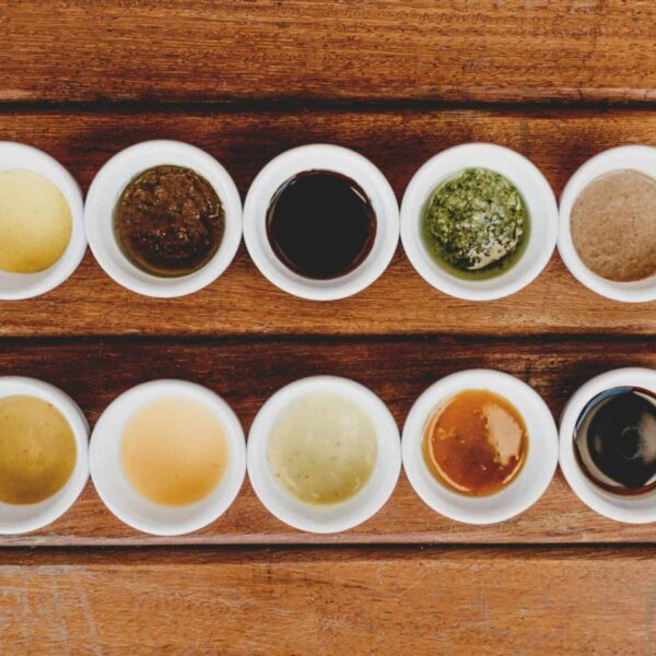 Assorted sauces and condiments displayed in bowls on a rustic wooden table.