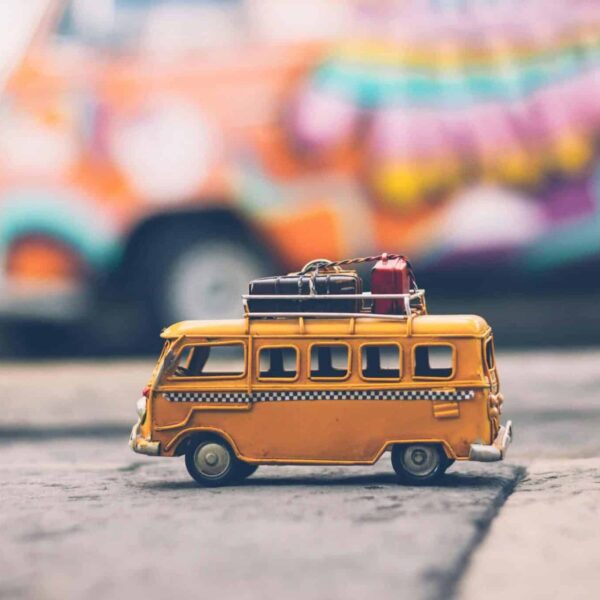 avoid jet lag, Close-up of a toy Volkswagen van with luggage, set against a colorful street backdrop, evoking summer travel vibes.