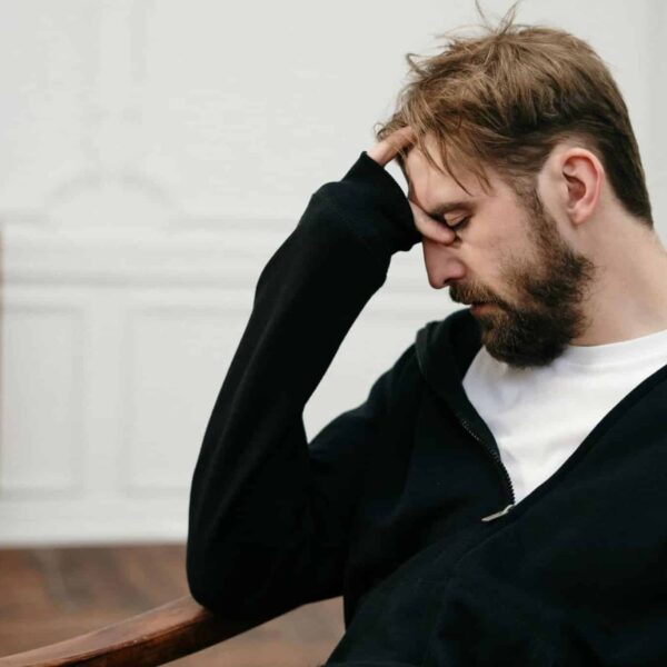 A man sits pensively with his hand on his face, capturing a moment of introspection and stress, sabotaging, relationship