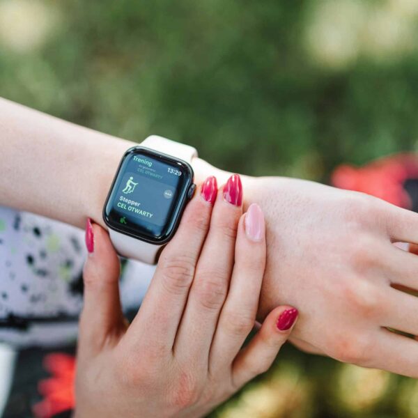 Close-up of a woman using a fitness tracking wearable smartwatch during exercise outdoors.