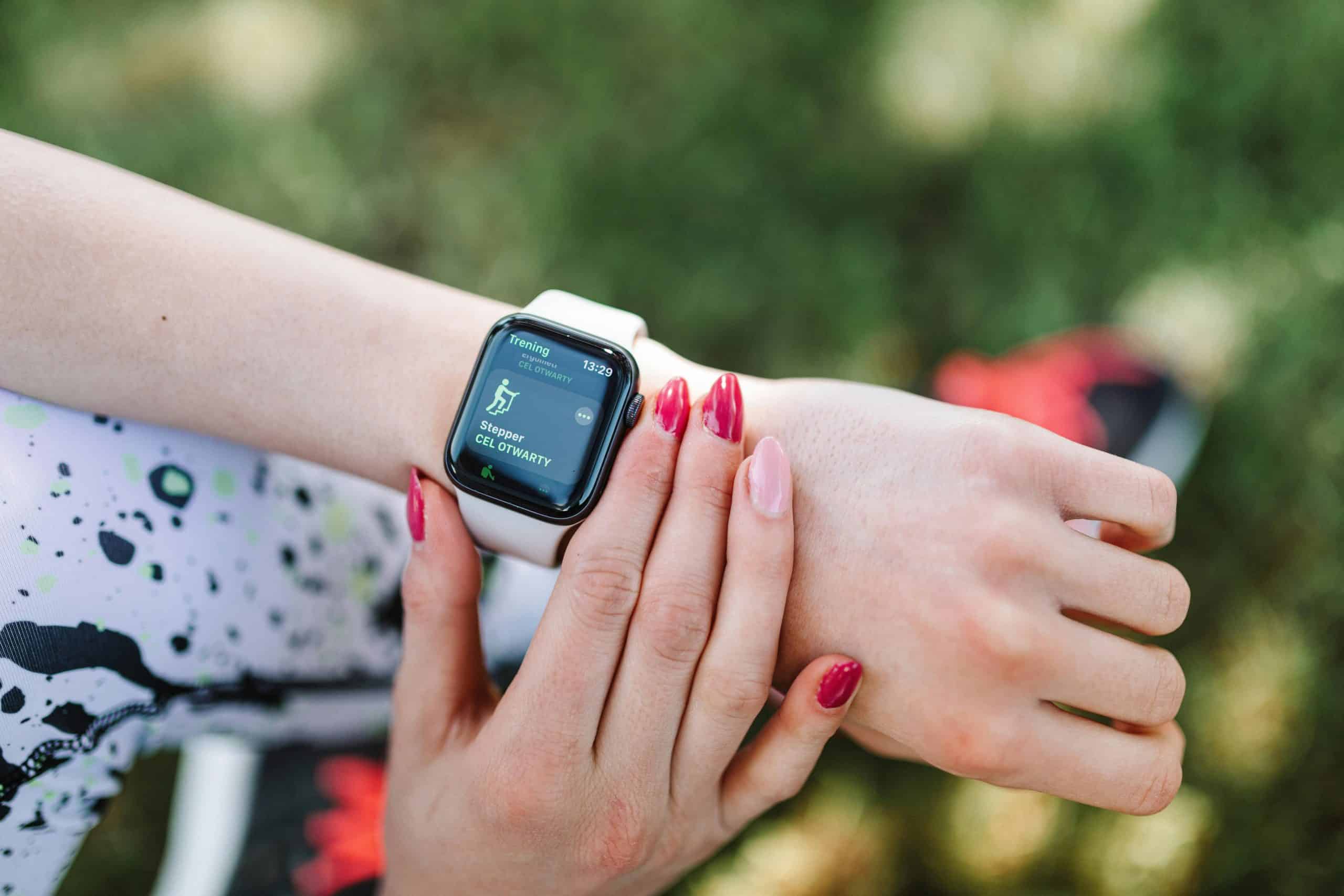 Close-up of a woman using a fitness tracking wearable smartwatch during exercise outdoors.