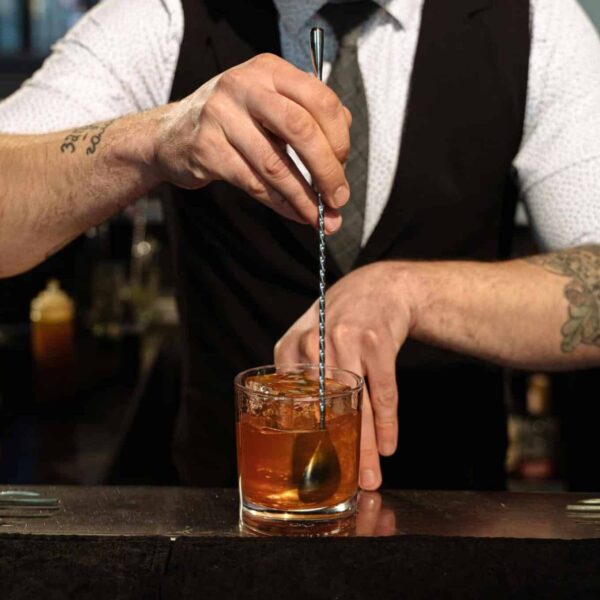 A bartender expertly blends a cocktail with ice, showcasing professional skills and style. Bartending