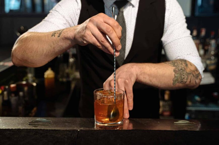 A bartender expertly blends a cocktail with ice, showcasing professional skills and style. Bartending