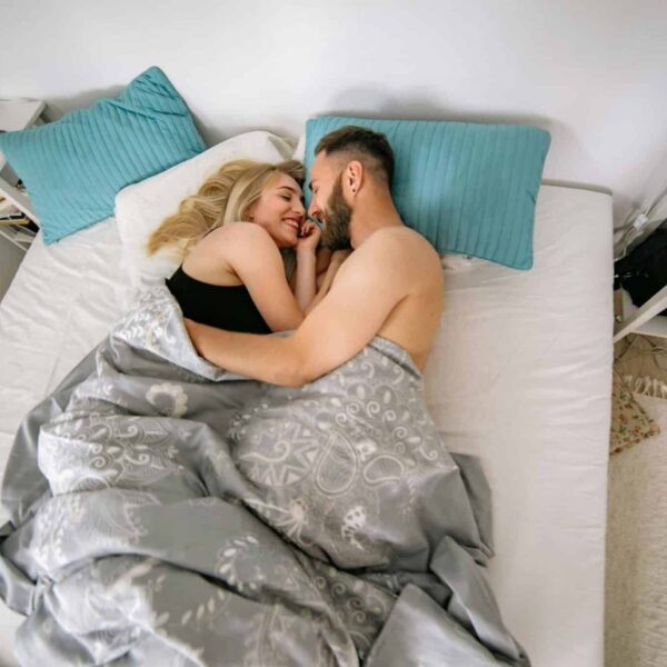 A happy couple embracing and smiling in a cozy bedroom, enhancing the warm home atmosphere. intimacy