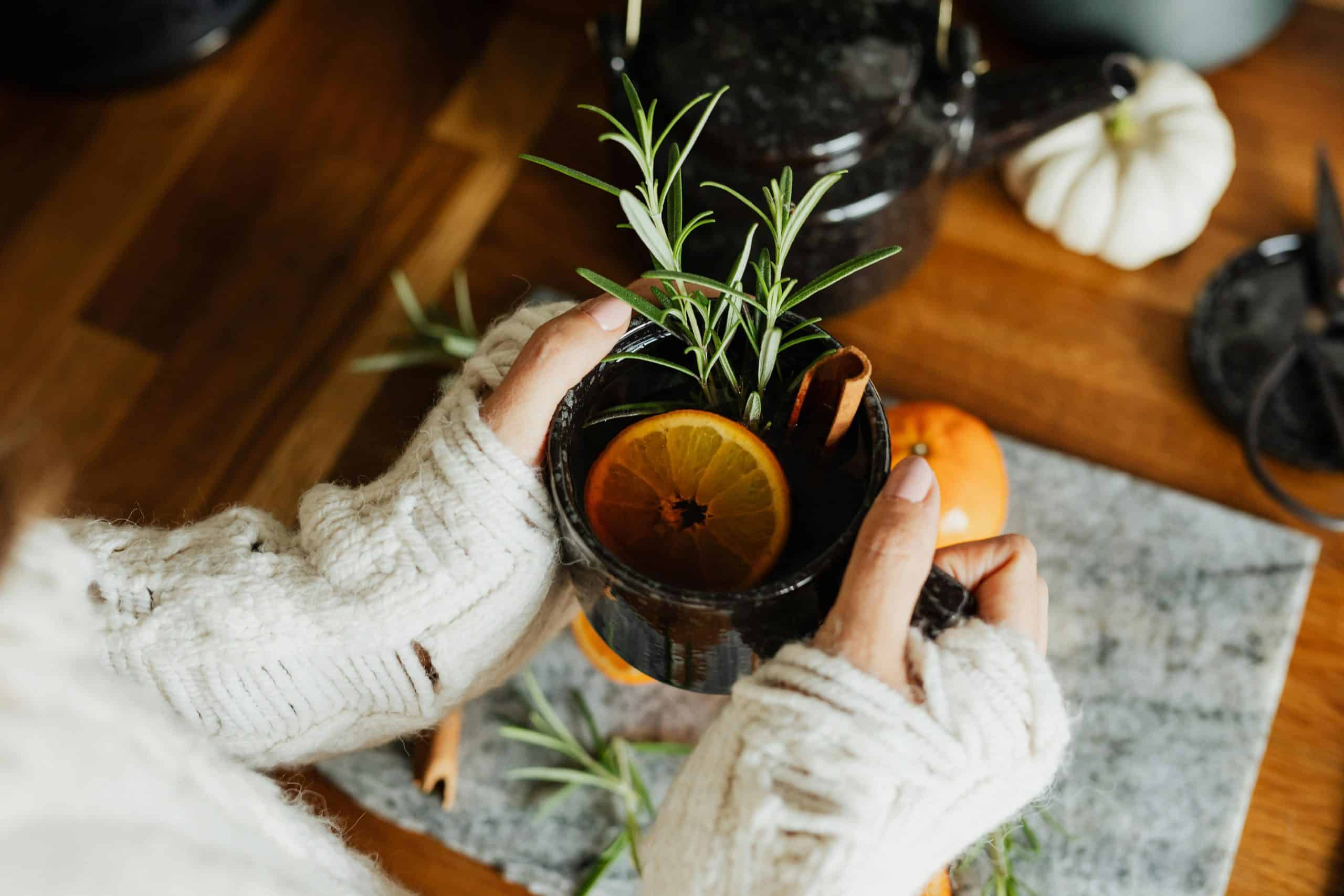 Warm cup of herbal tea with citrus and rosemary, perfect for a fall day indoors.