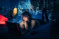 bed styling, A young woman in a cozy room, wearing headphones and using a laptop, surrounded by warm fairy lights.