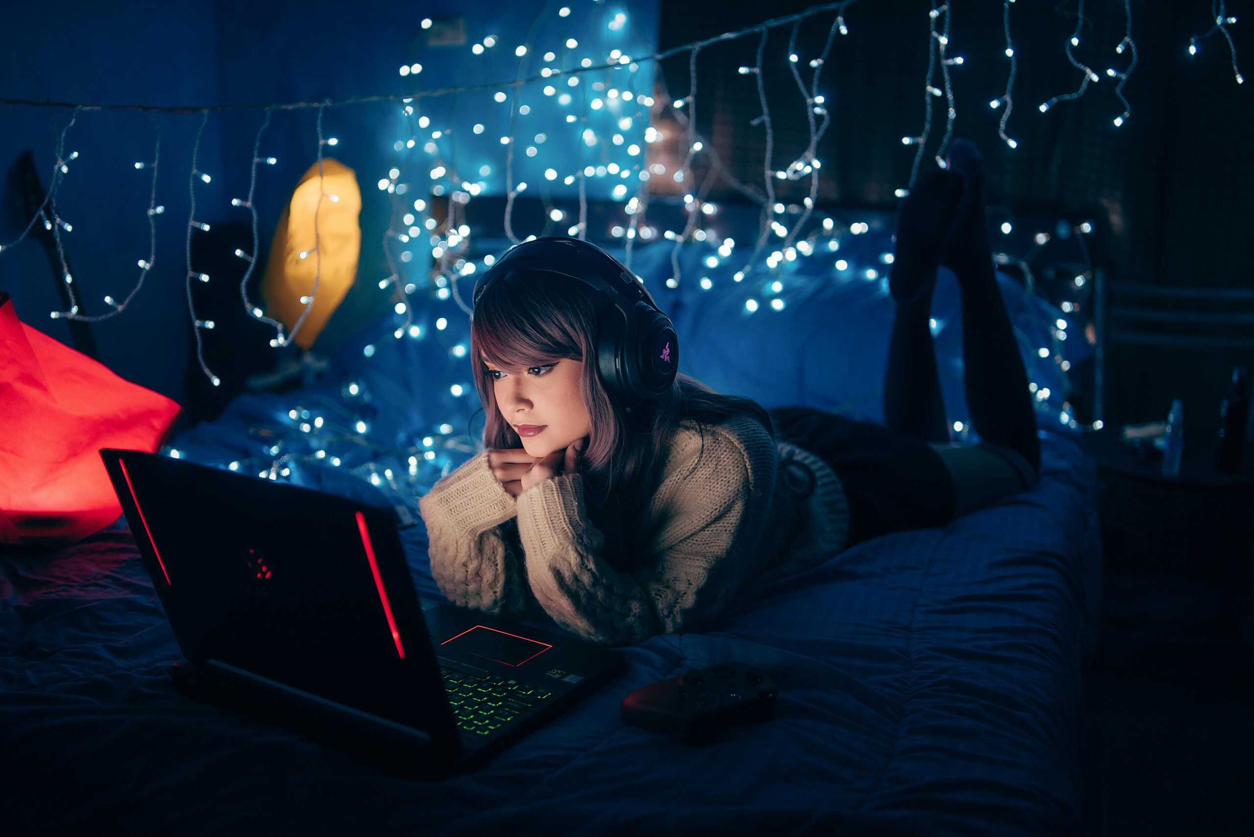 bed styling, A young woman in a cozy room, wearing headphones and using a laptop, surrounded by warm fairy lights.