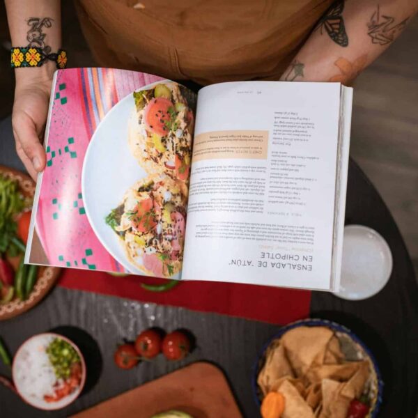 Close-up of chef holding cookbook over Mexican ingredients on table. Best cookbooks