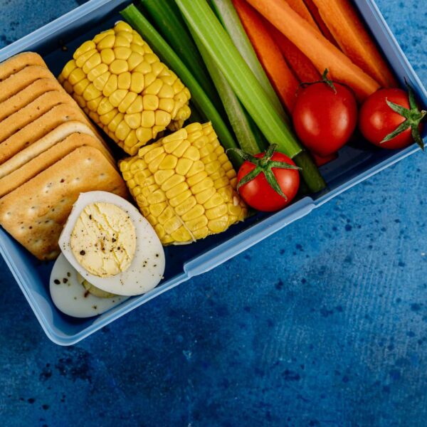 A vibrant lunchbox filled with nutritious vegetables, eggs, and crackers for a healthy meal. Lunchbox wellness