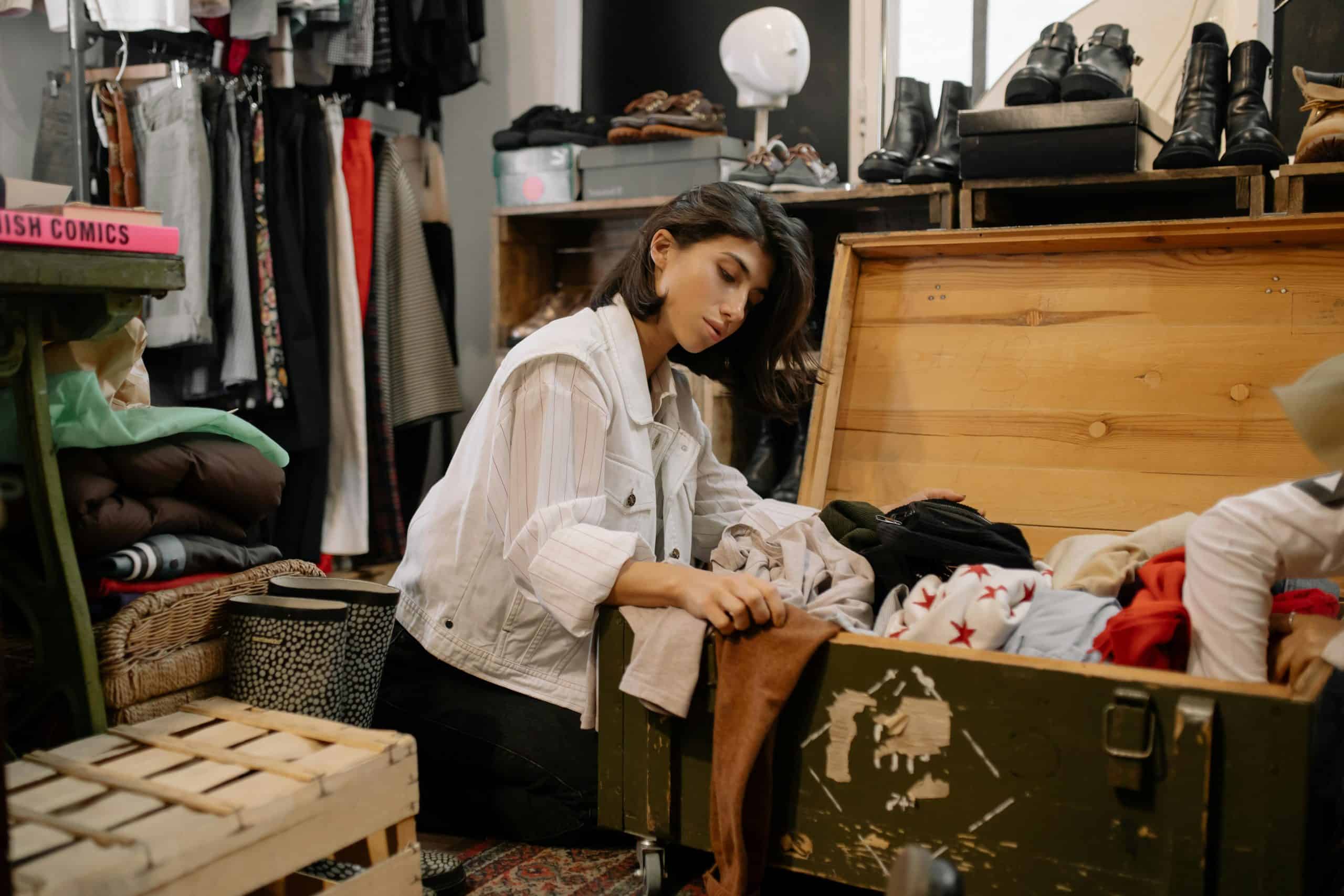 Young woman browsing vintage garments in a cozy thrift shop setting. second hand shopping