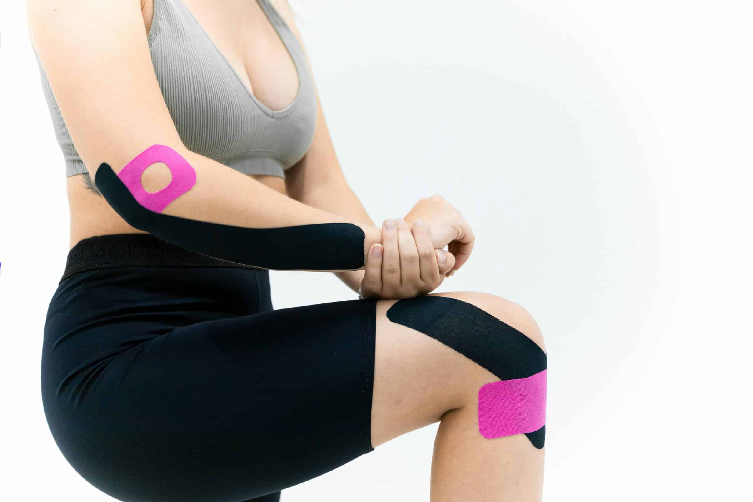 Close-up of a woman athlete applying kinesio tape for injury support. Fitness and therapeutic solution.