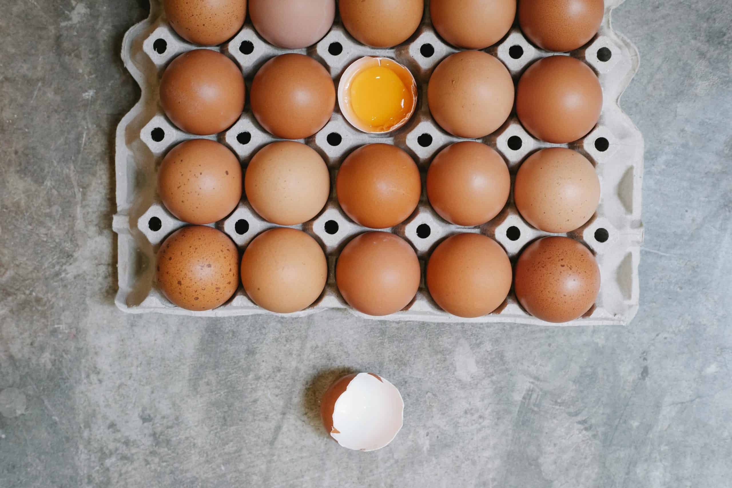 Top view of chicken eggs in rows in paper container placed on table for cooking. egg recall