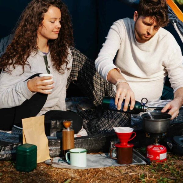 A couple brewing coffee with a chemex in a campsite, enjoying a relaxing outdoor experience. campsite safety