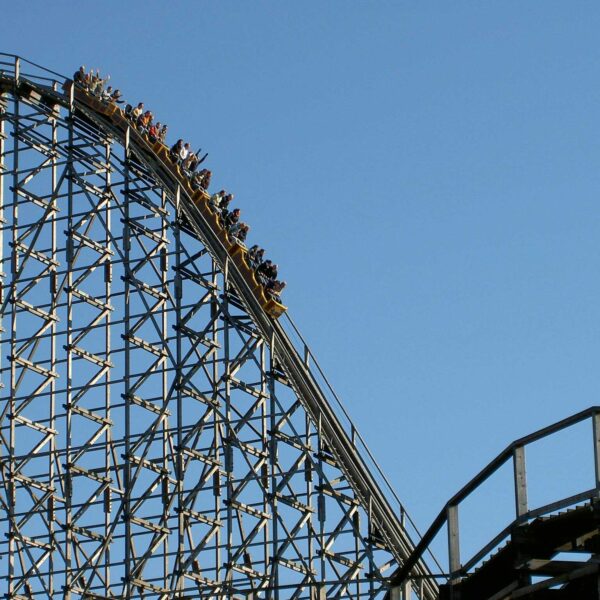 Experience the exhilarating thrill of a roller coaster ascending the steep peak at an amusement park. thrill seekers, roller coaster, roller coasters