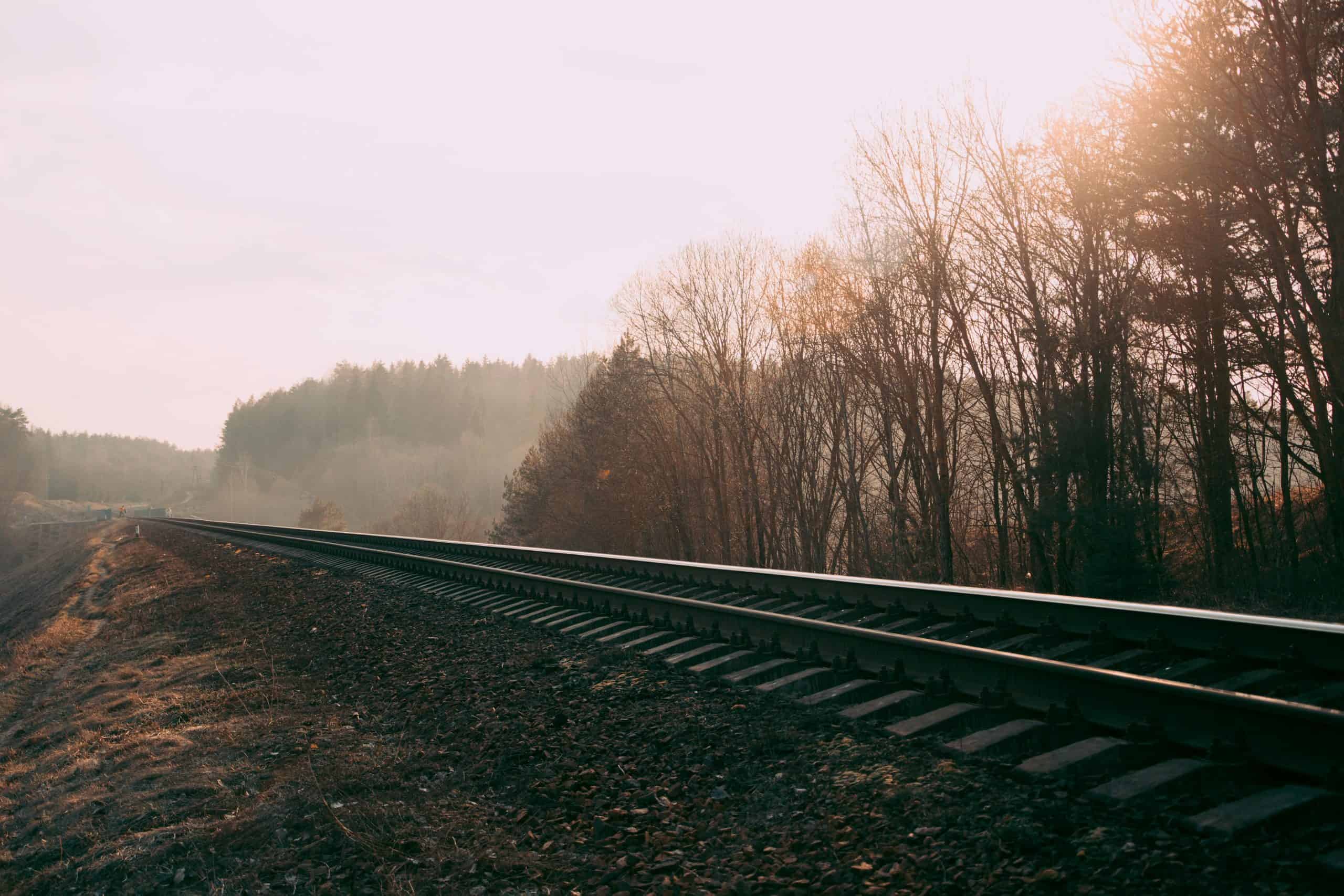 Foggy railway track through a misty autumn forest in Belarus, capturing serene nature and transportation scene.