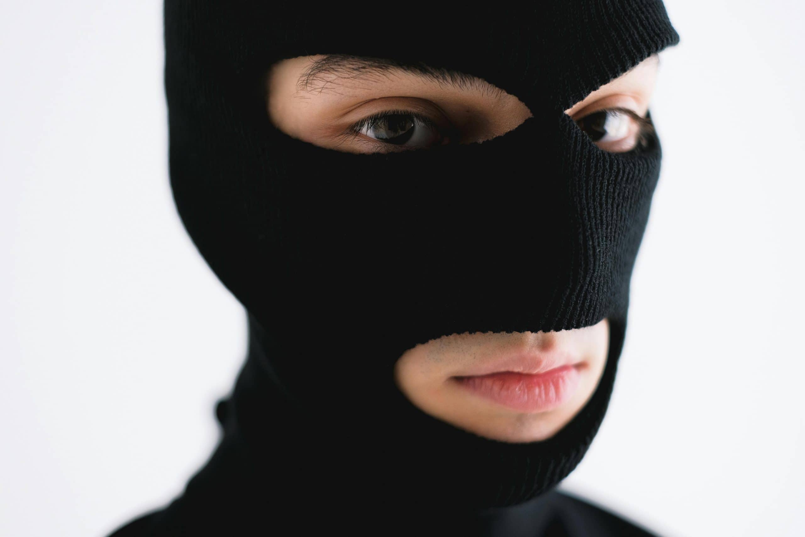 Close-up of a person wearing a black balaclava, conveying mystery or anonymity. Love, infatuation