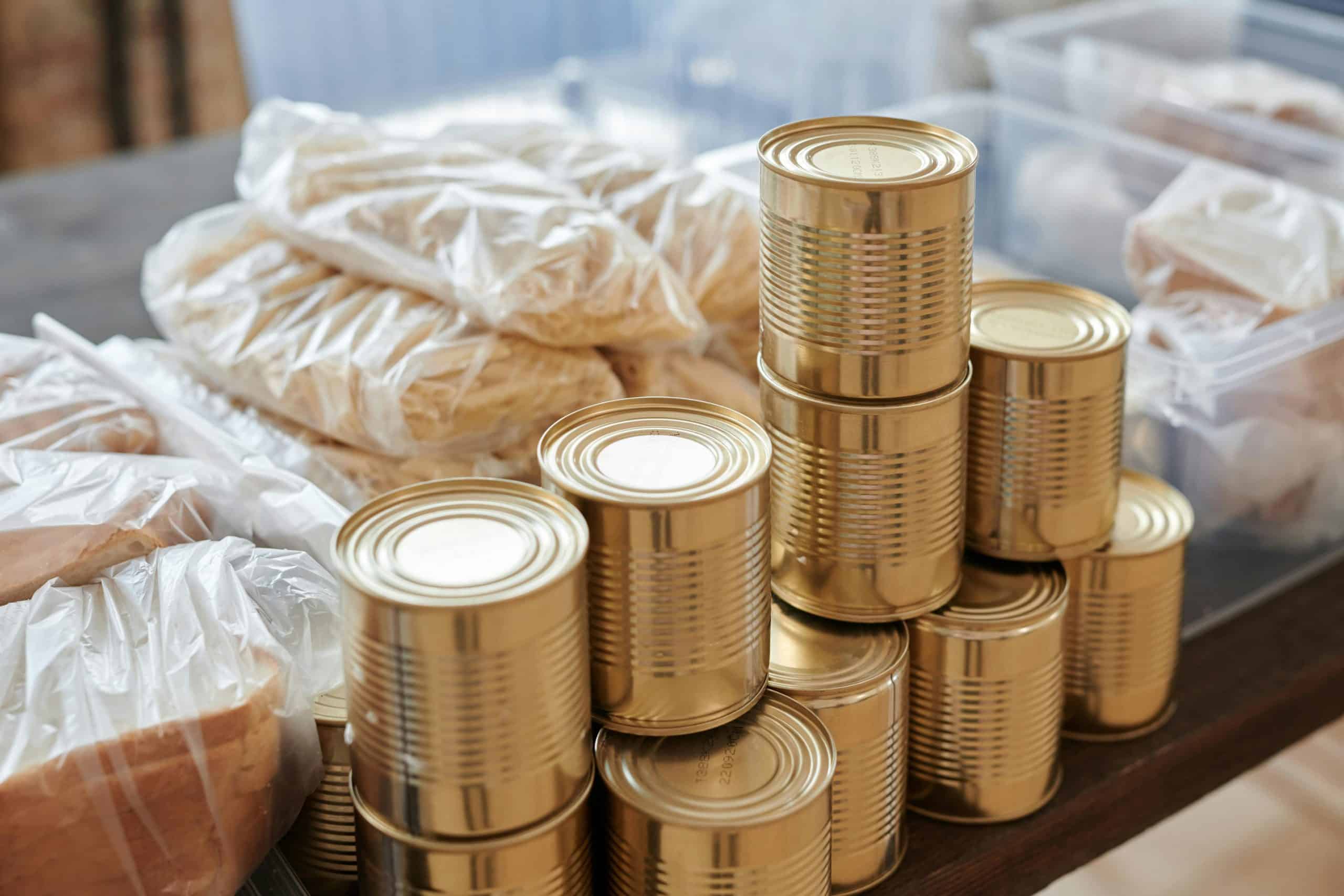A stack of canned goods and packaged foods on a table, perfect for donation drives. Hurricane-proofing supplies