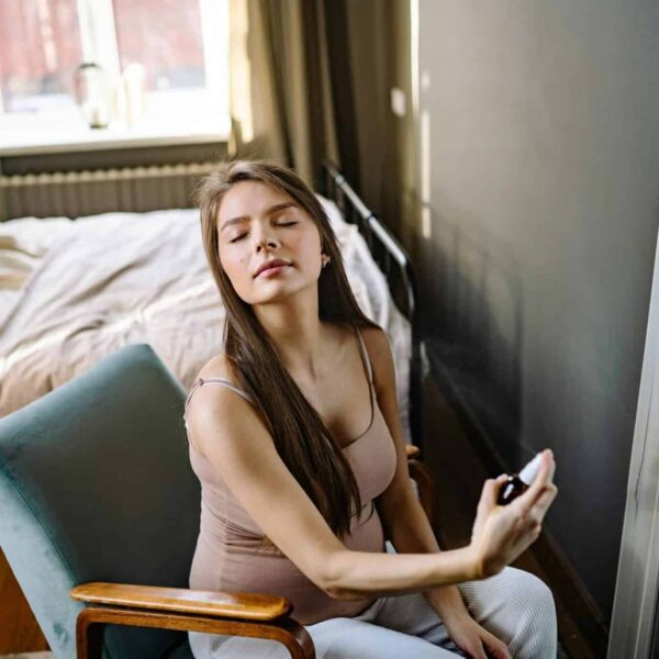 Pregnant woman sitting indoors, eyes closed, enjoying a refreshing fragrance. fragrances