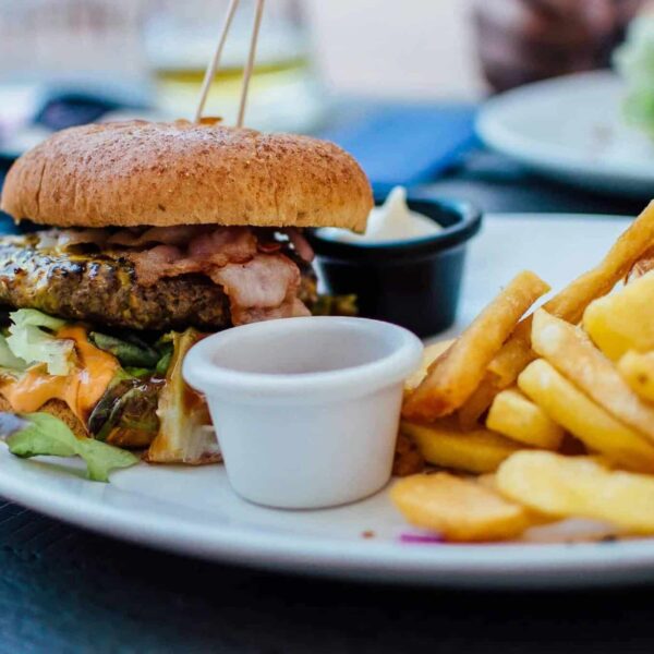 Close-up of a juicy burger and crispy fries served with sauces, perfect for a hearty meal. fast food