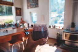 Hand holding a fresh berry smoothie in a sunlit, cozy kitchen interior setting. Quick breakfast