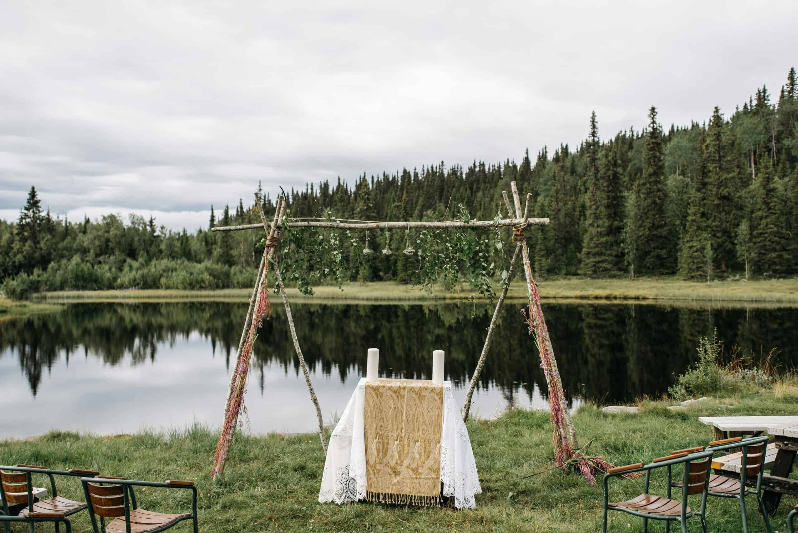 Beautiful outdoor wedding setup by a tranquil lake surrounded by lush greenery.