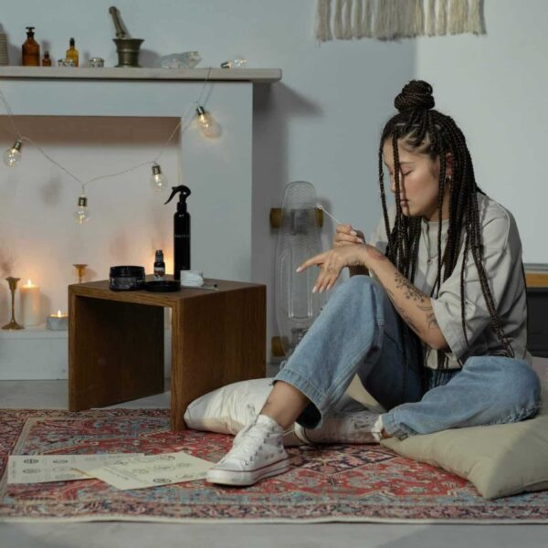 Woman with Afro braids in a cozy boho room. Featuring candles, plants, and cushions. boho braids