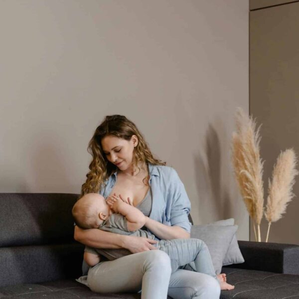 A tender moment of motherhood as a mother breastfeeds her baby on a sofa, indoors. breastfeeding