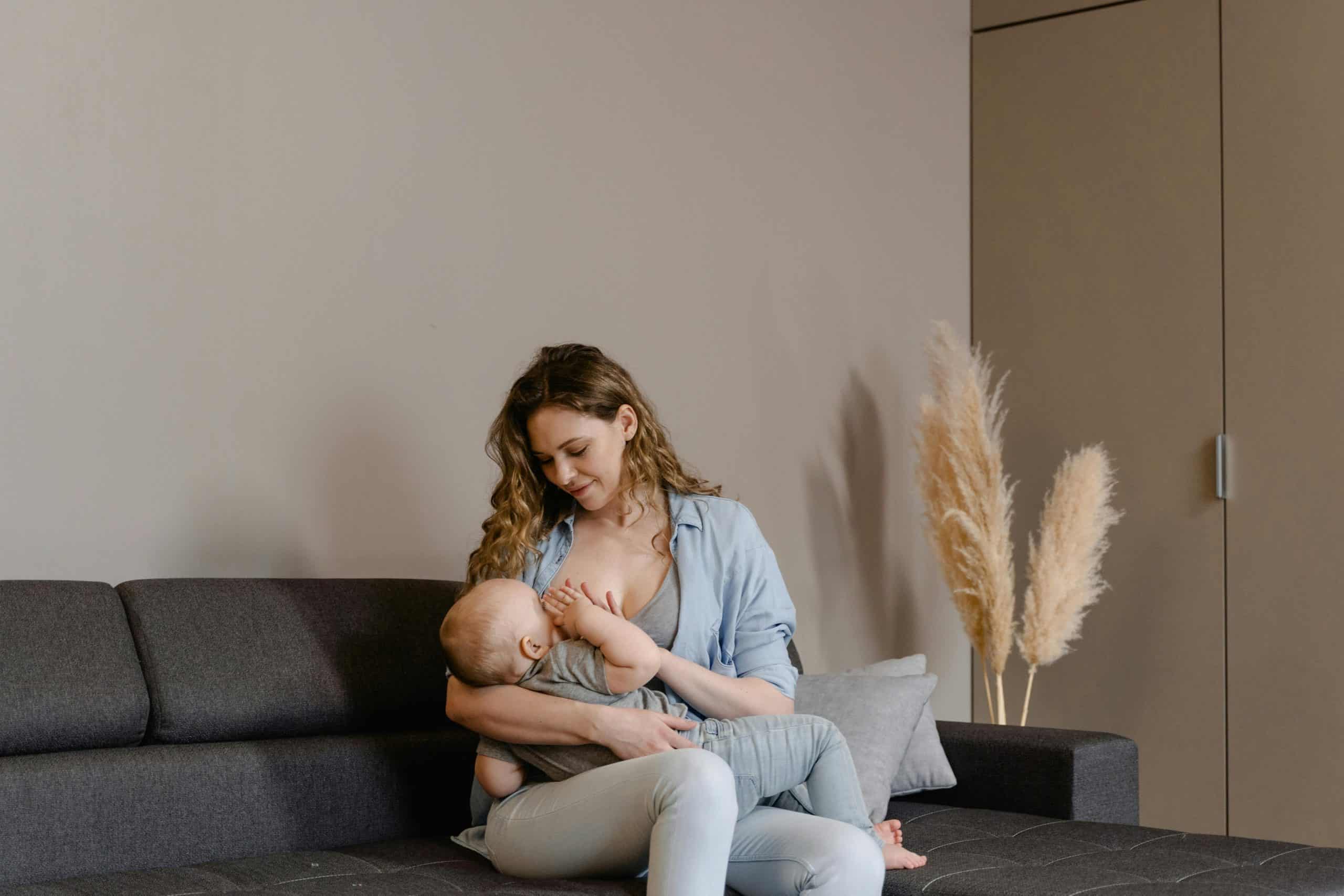 A tender moment of motherhood as a mother breastfeeds her baby on a sofa, indoors. breastfeeding