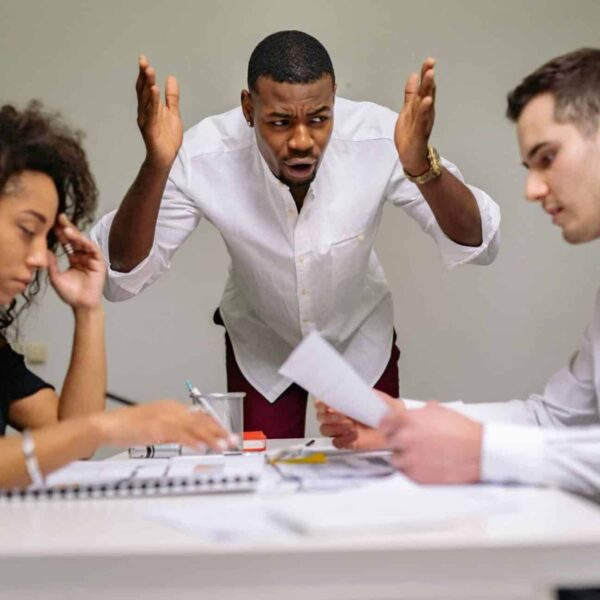 Three colleagues in a heated argument at the office, highlighting workplace stress.