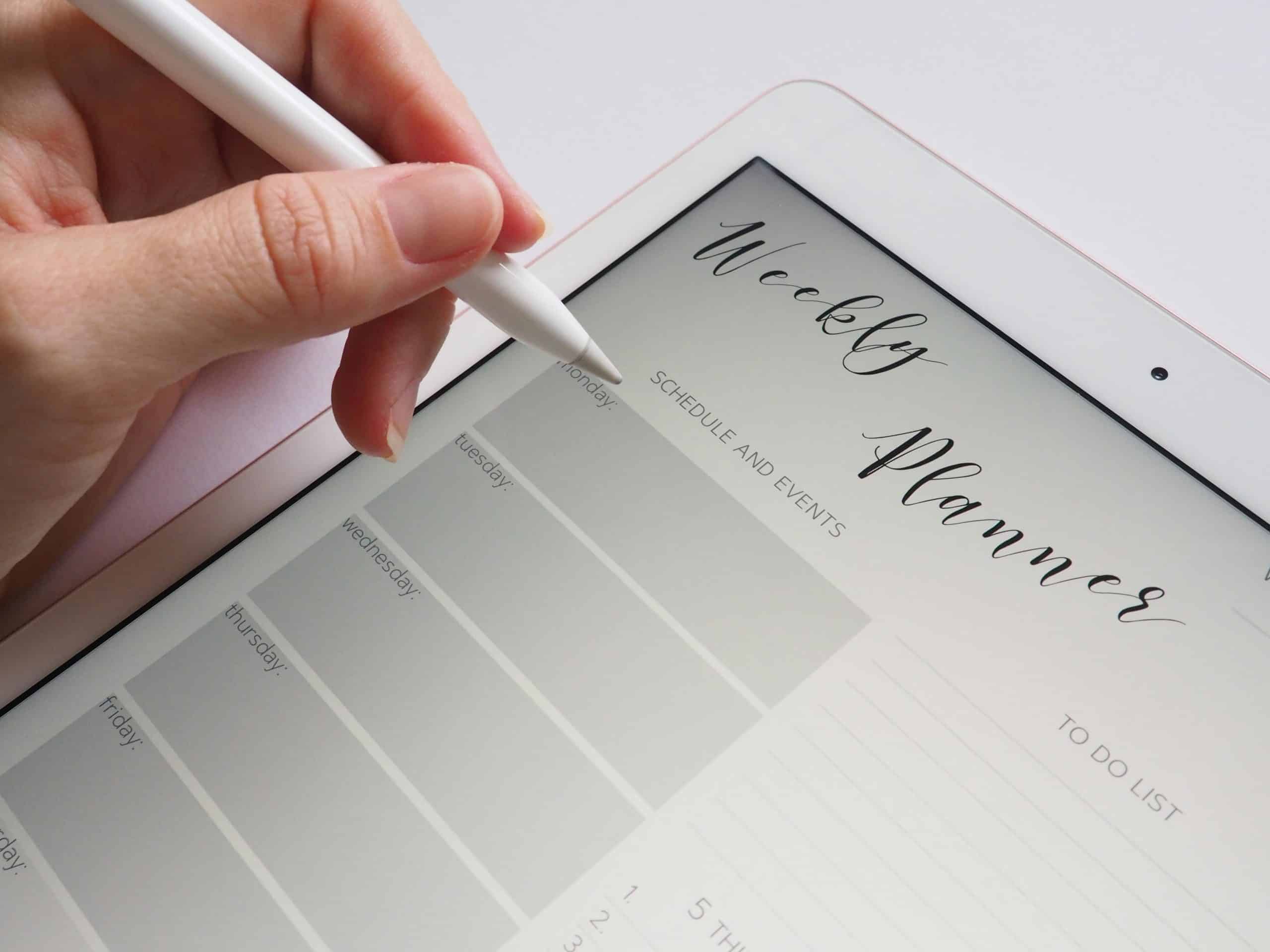 A stylus writing in a digital weekly planner on a tablet screen, ideal for organization. reduce stress