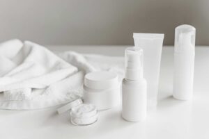 This photograph features a towel and a set of skincare products. Minimalist skincare involves using a few products that benefit skin.